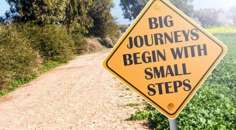 A sign beside road that saying big journeys begin with small steps